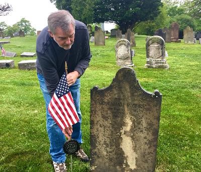 Man placing flag on a grave